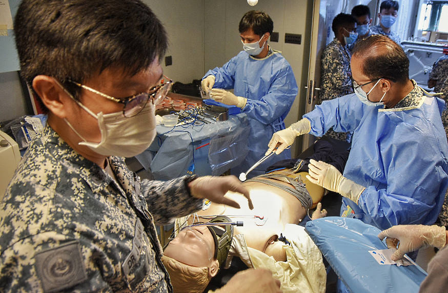 Performing surgical procedures for a casualty at the frigate's medical centre, with the casualty simulated by a High Fidelity Medical Simulation Mannequin.