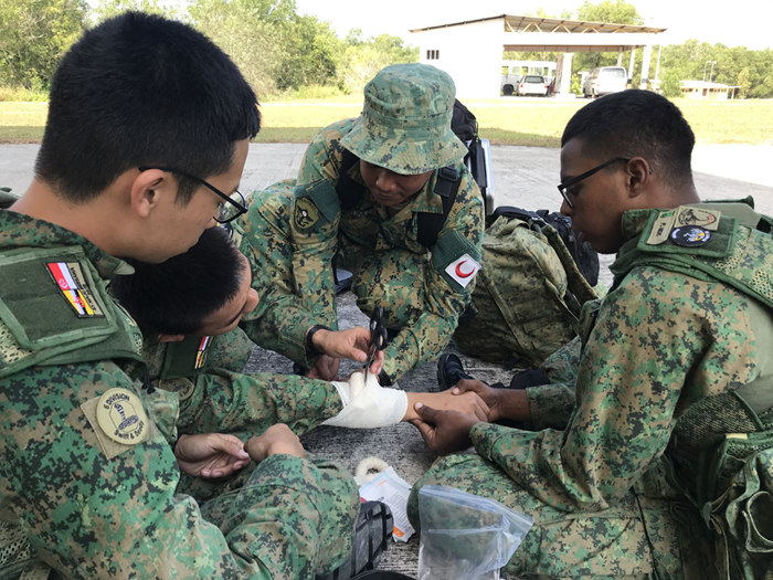 3SG Alfred Ho Zheng Ting (first from left), exchanging medical knowledge and bandage wrapping technique with the medics from RBLF.