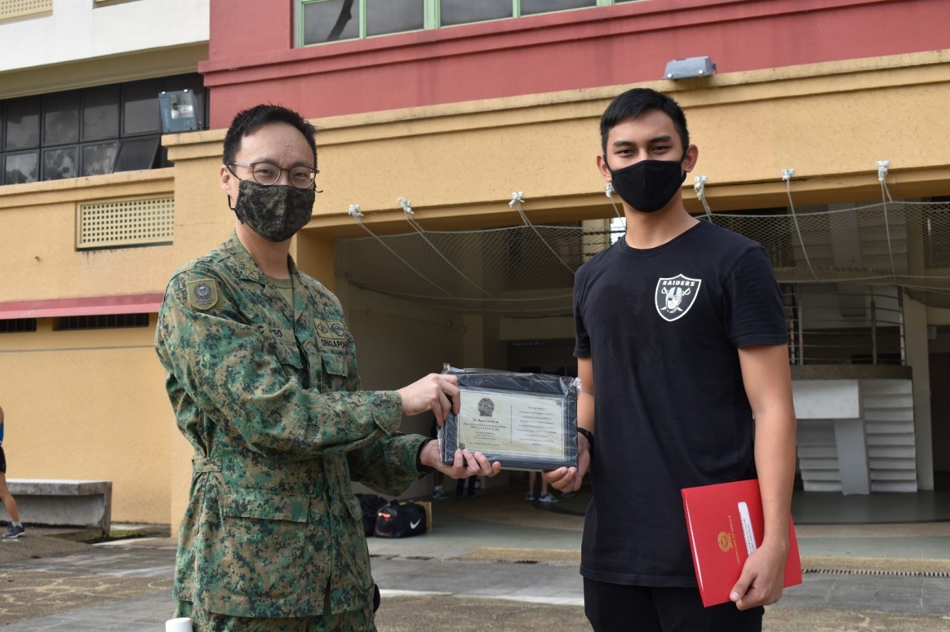 LTC Teo Chun Jin (left) presenting the ORD plaque and certificate to one of the soldiers.