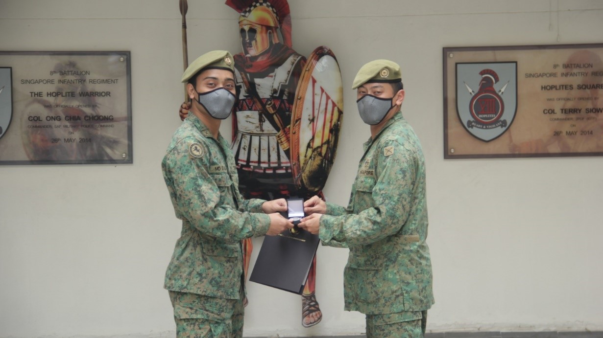 LTC Giam (right) presenting the CO coin to one of his troopers.