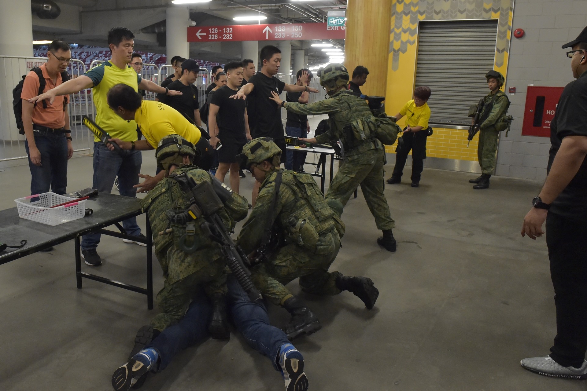 Soldiers from the 3rd Battalion, Singapore Infantry Regiment (3 SIR) and security personnel from Sports Hub at the personnel access control point, apprehending a member of the public who did not comply with the instructions.