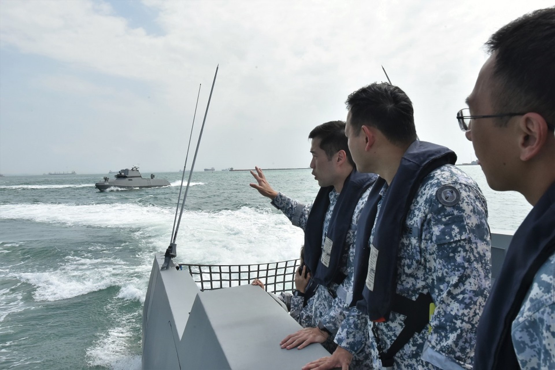 Lieutenant Colonel Tan Kailing, Commanding Officer Unmanned Surface Vessel (USV) Squadron (left) briefing Mr Zaqy (middle) on the capabilities of the USV in the conduct of maritime security operations.