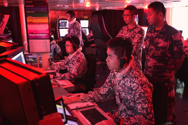 A PLA(N) officer (right) observing the conduct of the Air Defence exercise in the Combat Information Centre onboard RSS Intrepid.