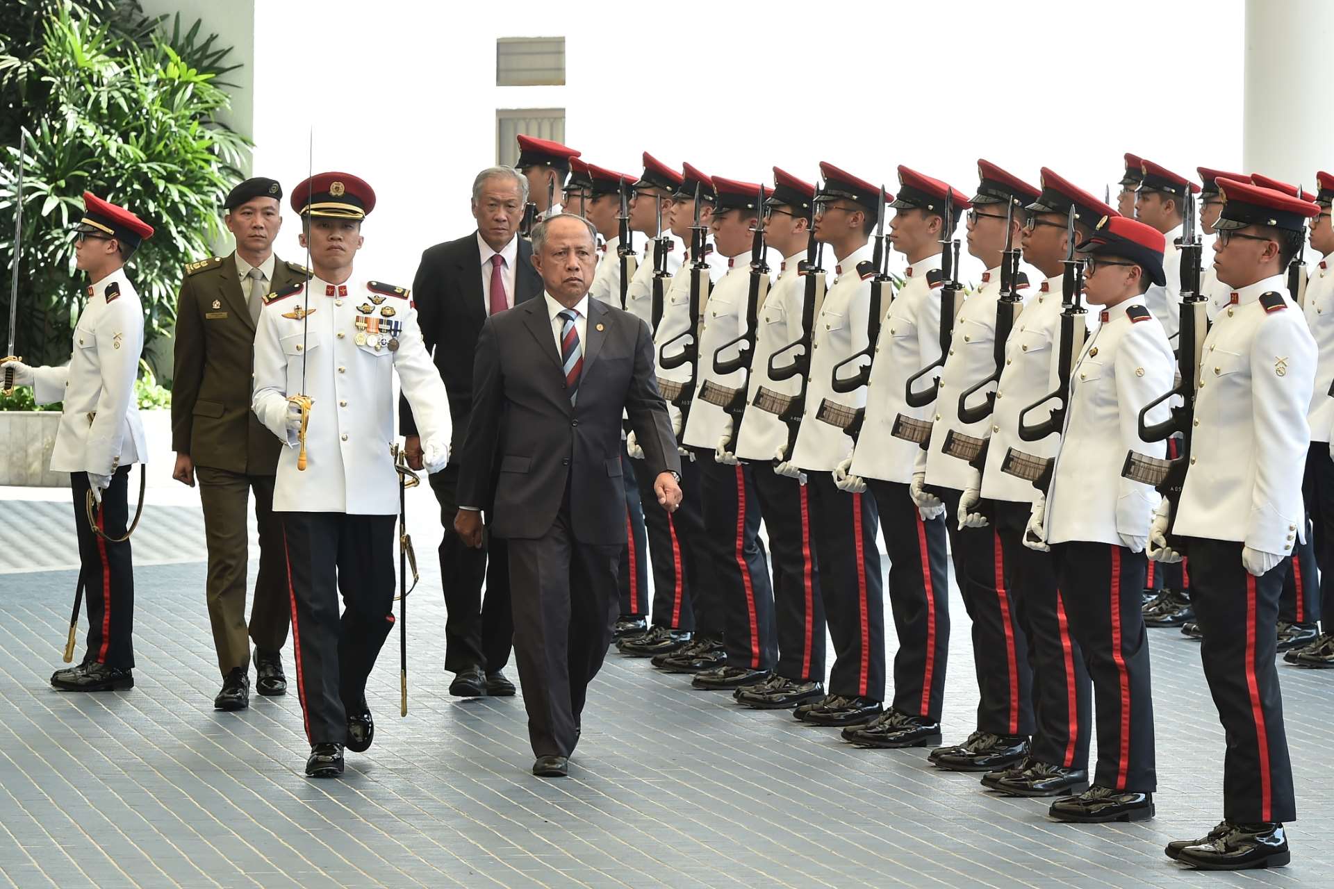 Pehin MG(Rtd) Halbi (fifth from left), accompanied by Dr Ng (fourth from left), reviewing the Guard of Honour at MINDEF.