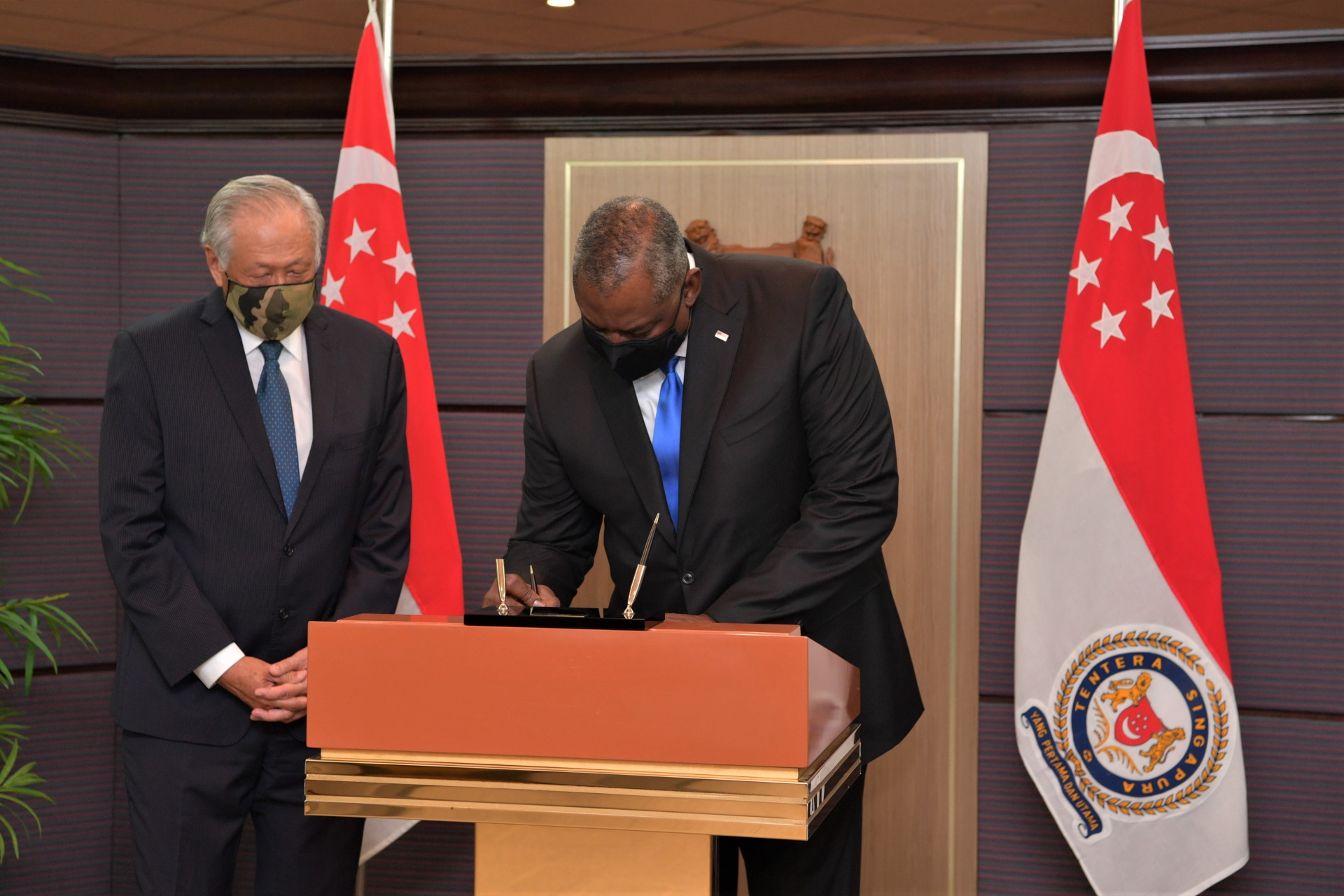 Secretary Austin signing the MINDEF guestbook. On his right is Minister for Defence Dr Ng Eng Hen.