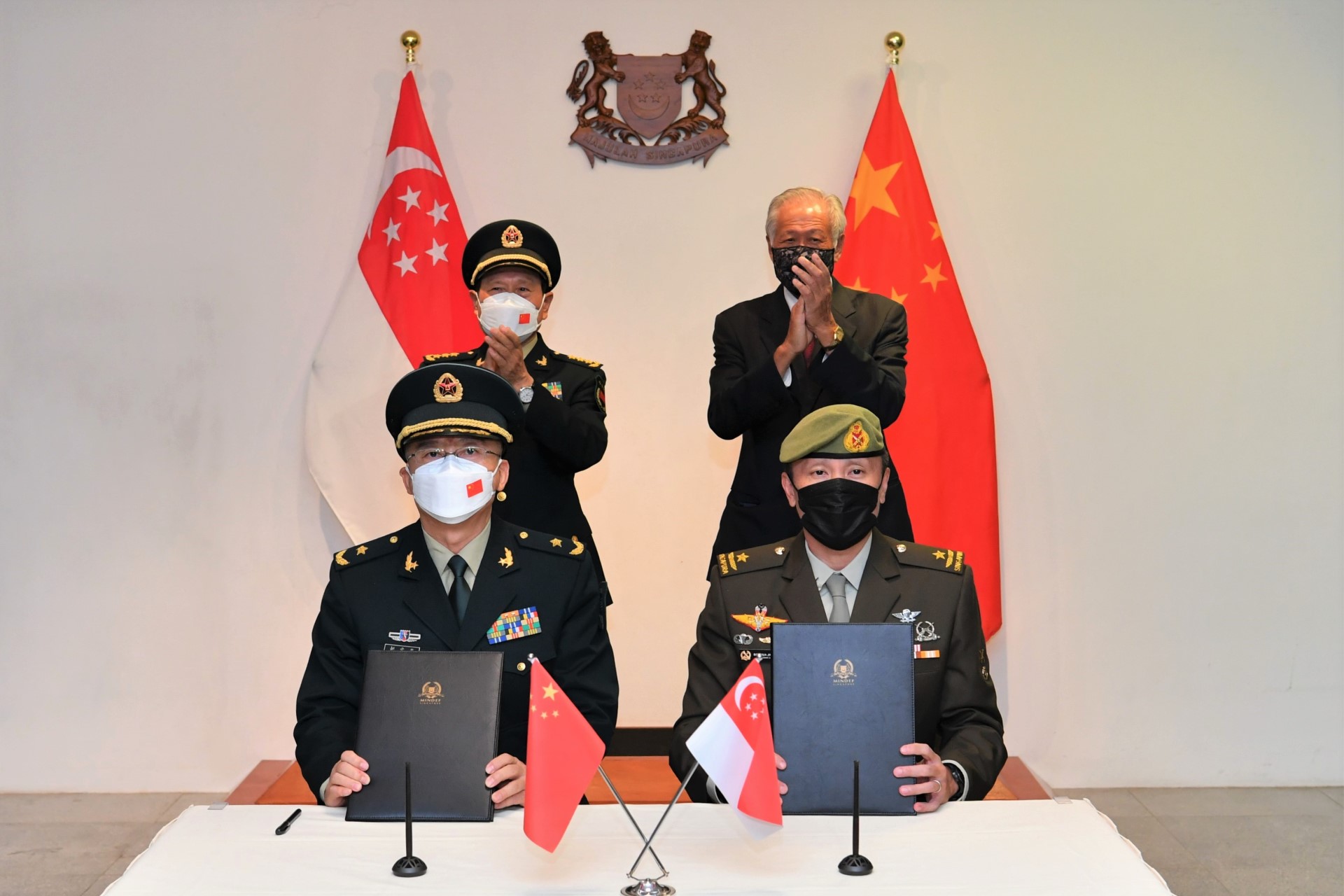 Dr Ng (standing on the right) and GEN Wei (standing on the left) witnessing the signing of the MOU for Academic Cooperation between the Singapore Armed Forces Training Institute (SAFTI) Military Institute and the Academy of Military Sciences...
