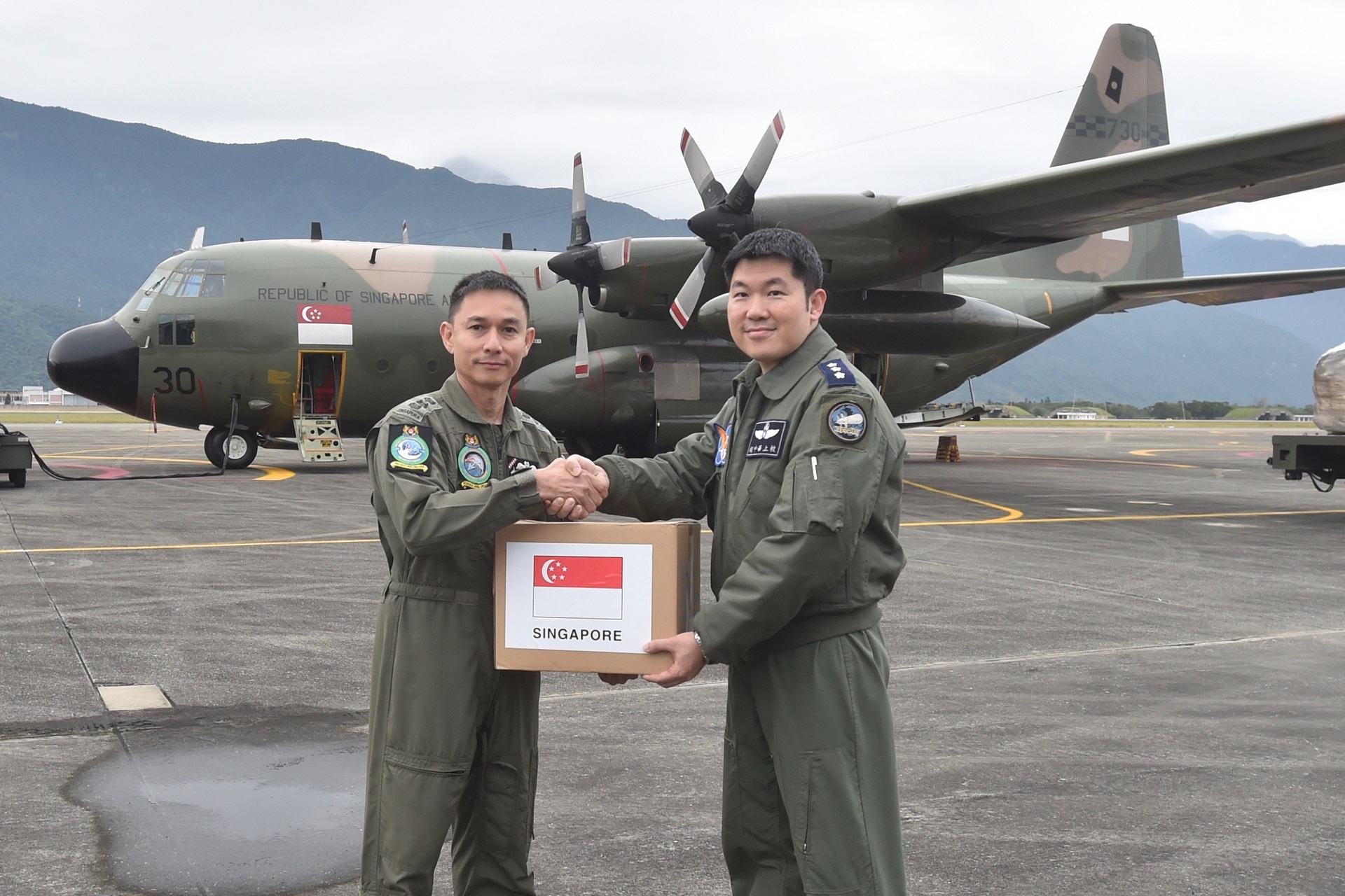 The SAF Mission Commander, Colonel (COL) Zakir Hamid (left), Commander Transport Group, Air Combat Command, handing over the aid supplies to Director of Ops, 5th Wing Command, COL Hu Chung-Hua.