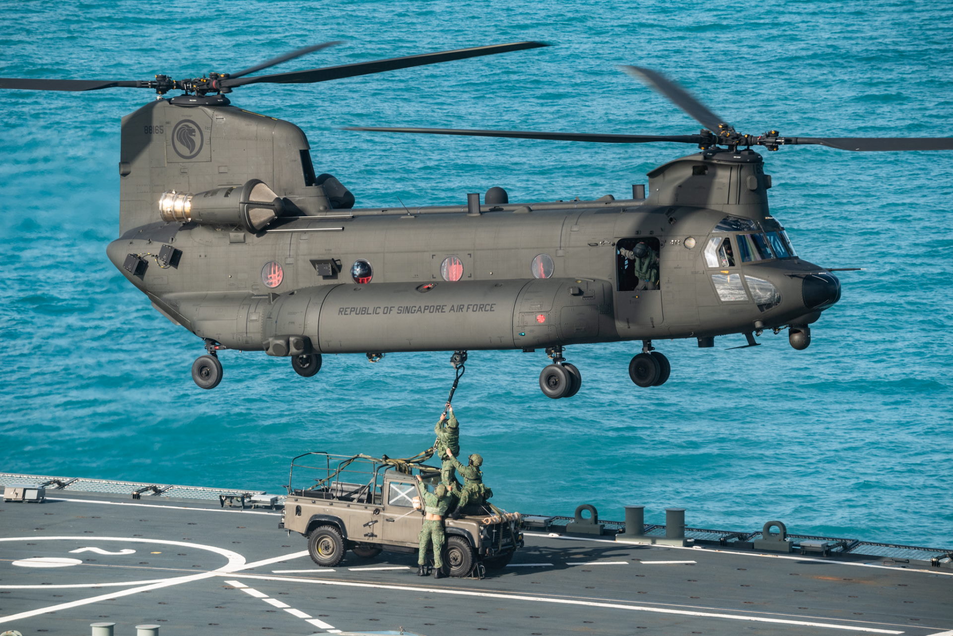 Exercise participants from the Army rigging a land rover on board the RSN's RSS Endeavour to an RSAF CH-47F Chinook helicopter during a replenishment serial as part of XWB21. 