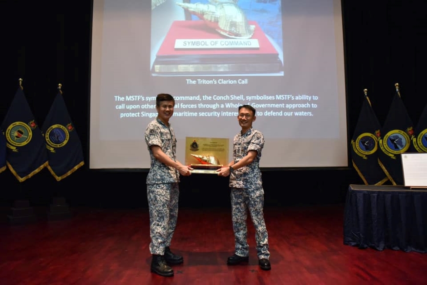 RADM Seah hands over the MSTF symbol of command - the Triton's Clarion Call - to COL Yong.